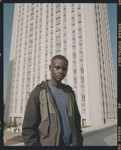 Low angle view of young man standing against buildings in city