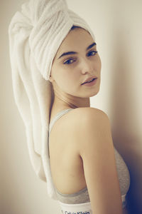 Portrait of young woman standing against wall