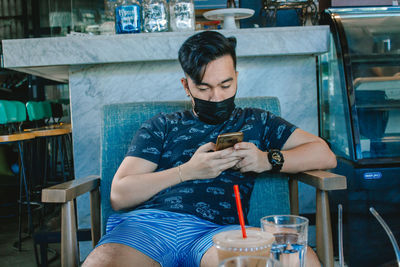 Full length of young man sitting in restaurant