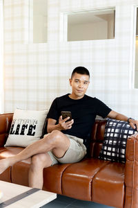 Full length of man sitting on sofa at home