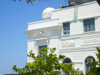 Low angle view of trees and building against sky