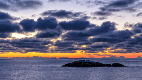 Scenic view of sea against dramatic sky during sunset