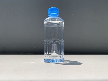 Close-up of water bottle on table against blue background