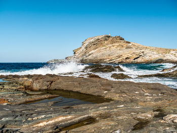 Rock formation on beach against clear blue sky