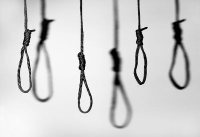 Close-up of chain hanging on rope against wall