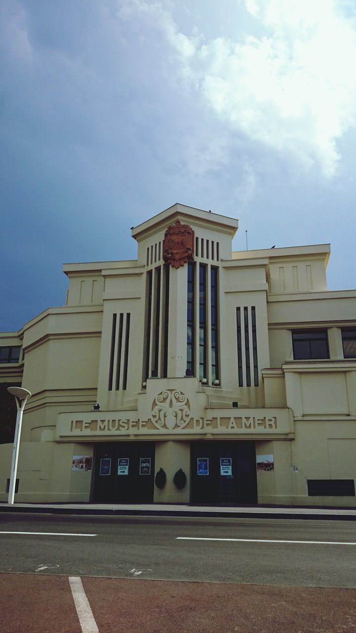 architecture, building exterior, built structure, sky, text, street, western script, low angle view, cloud - sky, road, facade, window, day, building, city, outdoors, cloud, transportation, communication, no people