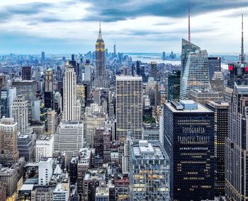 Aerial view of city buildings against cloudy sky