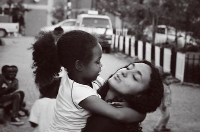 Young woman carrying girl while standing on road