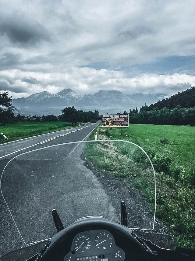 CAR ON ROAD AGAINST CLOUDY SKY