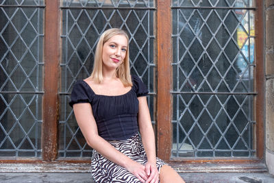 Portrait of young woman standing against wall