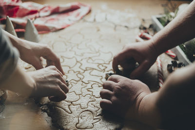 Mom and daughter cooking christmas cookies, cut out different shapes on wooden table at kitchen