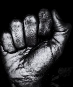 Close-up of man holding hands against black background