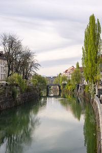 Arch bridge over river by building against sky