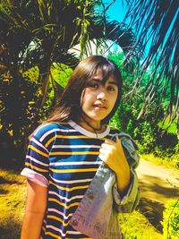 Portrait of smiling young woman standing against plants