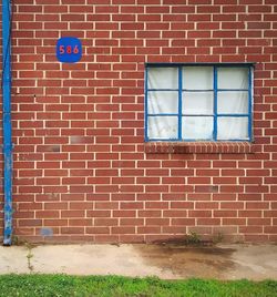 Old red brick apartment building exterior wall and window with blue trim.