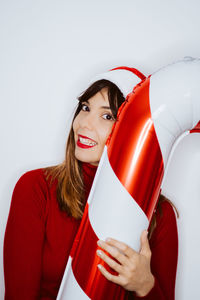 Portrait of smiling woman holding balloon while standing against white background
