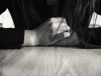 Midsection of woman leaning on wooden table