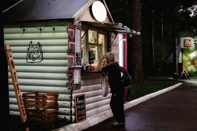 Side view of woman standing against illuminated building