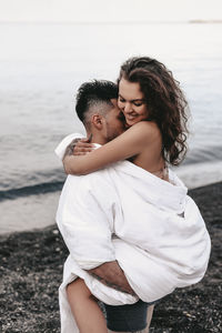 A couple in love spend the night at the sea, kissing and hugging on the beach covered with a blanket