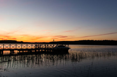 Silhouette boat in lake against sky during sunset