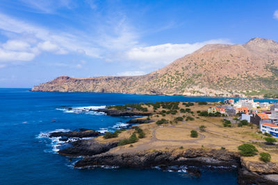 Scenic view of sea and mountains against blue sky