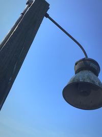 Low angle view of lighting equipment against clear blue sky