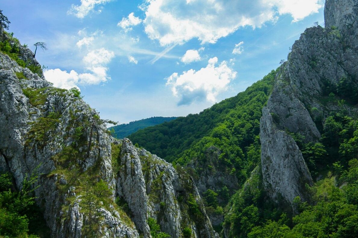 mountain, sky, tranquility, scenics, tranquil scene, beauty in nature, tree, nature, rock formation, cloud, rock - object, cloud - sky, landscape, non-urban scene, rocky mountains, mountain range, day, green color, low angle view, outdoors