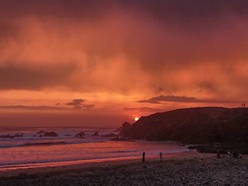 Scenic view of beach against sky at sunset