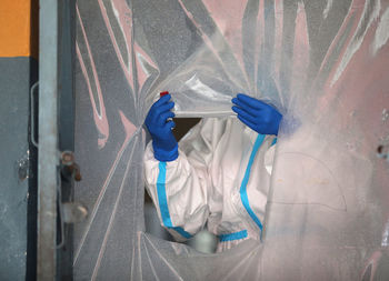 Midsection of doctor wearing protective suit standing at hospital