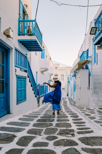 Rear view of woman walking on alley amidst buildings