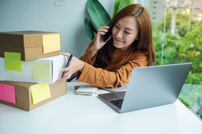 Portrait of young woman using laptop at table