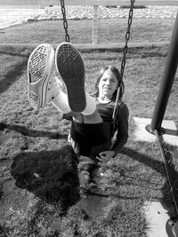 Full length portrait of girl on swing in playground