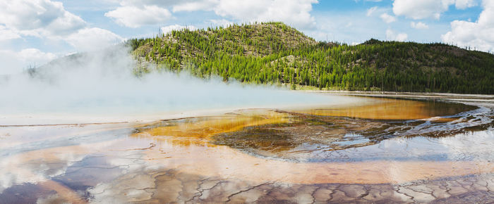 Scenic view of hot springs at yellowstone national park against cloudy sky