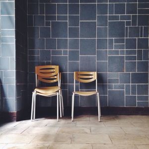 Empty chairs against tiled wall