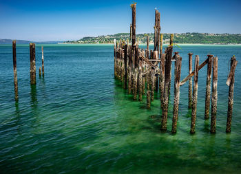 Wooden posts in sea against sky