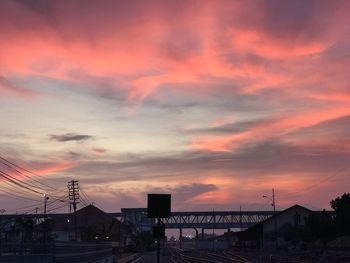 Silhouette city against dramatic sky during sunset