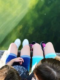 Low section of girls sitting over lake