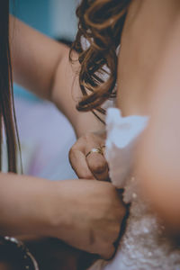 Cropped hands assisting bride for dressing