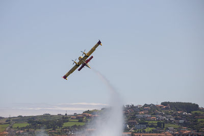 Airplane flying in city against clear sky