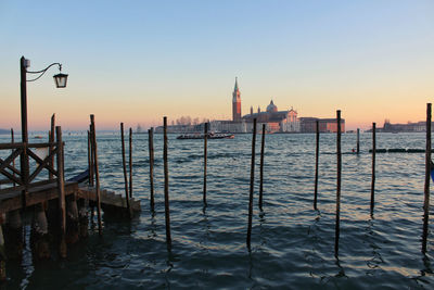 Wooden posts in sea against clear sky