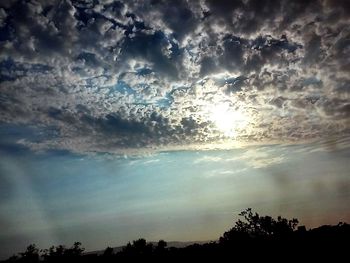 Silhouette of trees against cloudy sky