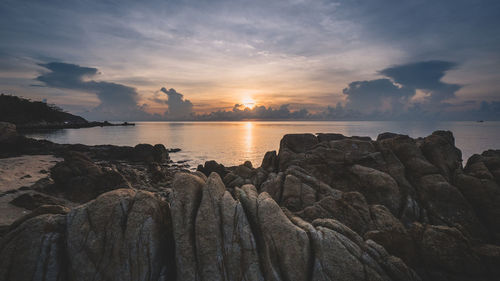 Island scenic sunrise at a bay with beautiful sky and textured rock foreground. koh samui, thailand.