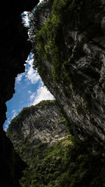 Low angle view of rocks on cliff against sky