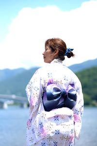 Rear view of woman standing on mountain against sky