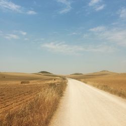 Road amidst field against sky