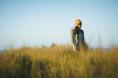 Woman standing by plants against clear sky