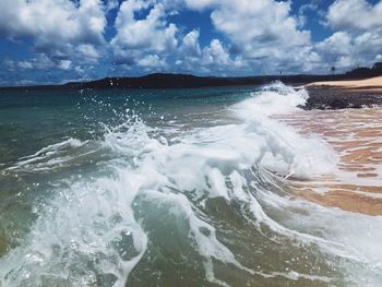 Waves splashing on sea against sky