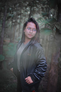 Teenager girl looking away while standing in forest