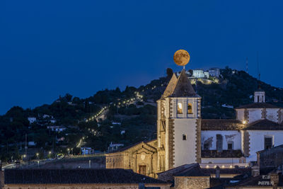 Illuminated buildings against blue sky at night