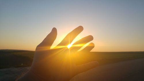 Close-up of hand against sunset